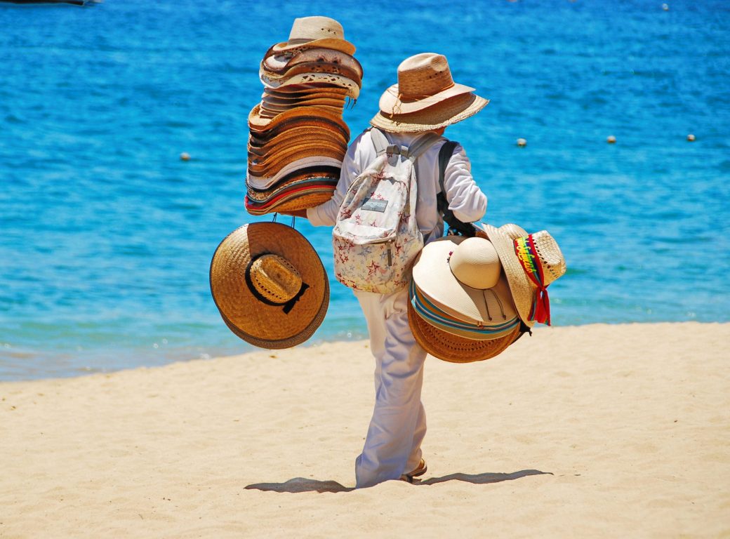 EWKTGM Local man selling straw hats on the beach in Cabo San Lucas, Mexico.